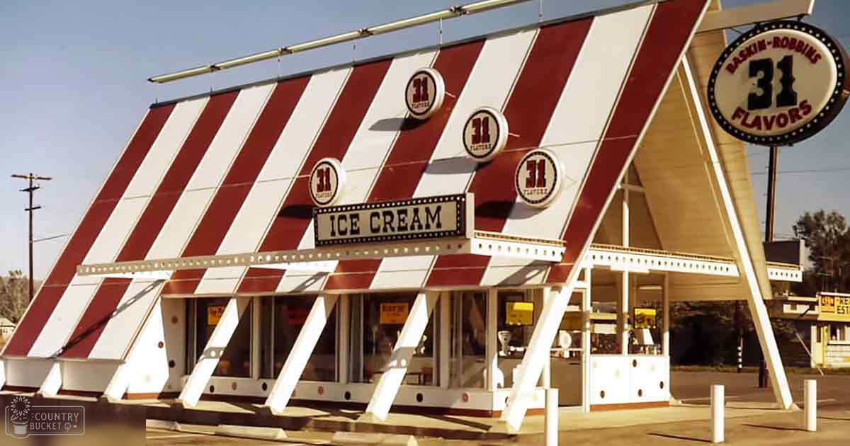 A Baskin-Robbins ice cream shop with a red and white striped awning in an outdoor setting under a clear blue sky on a sunny day.