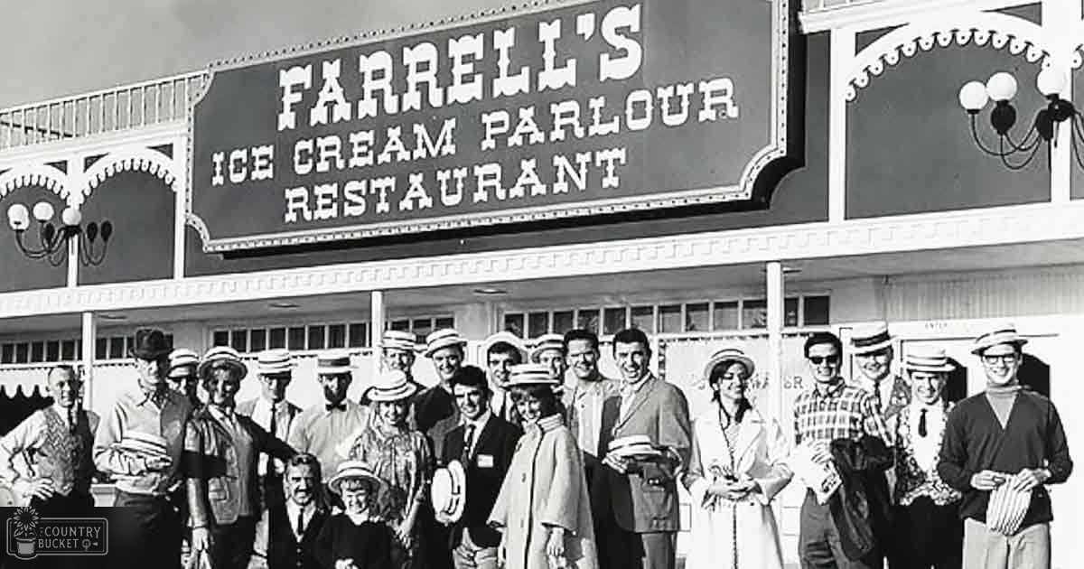 A group photo in front of Farrell's Ice Cream Parlour Restaurant, with adults and young adults dressed in mid-20th century attire under clear skies with natural sunlight.