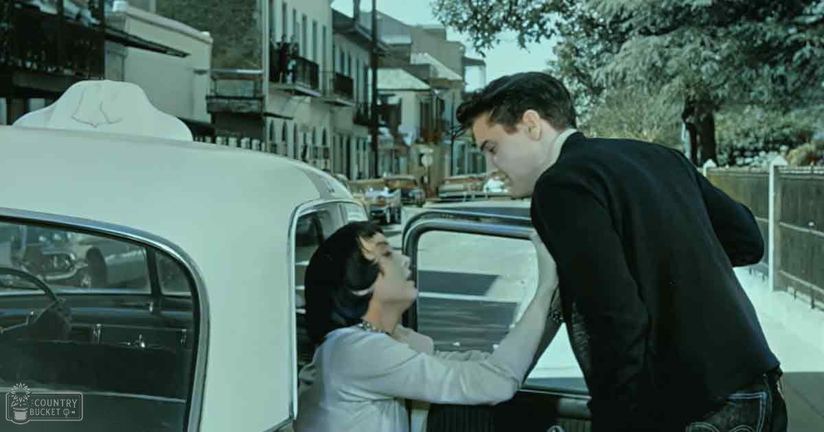 A winter street scene from 'The Great Gatsby' with a white vintage car labeled 'Molly Didd,' two individuals in period attire, and urban architecture indicative of the 1920s era.