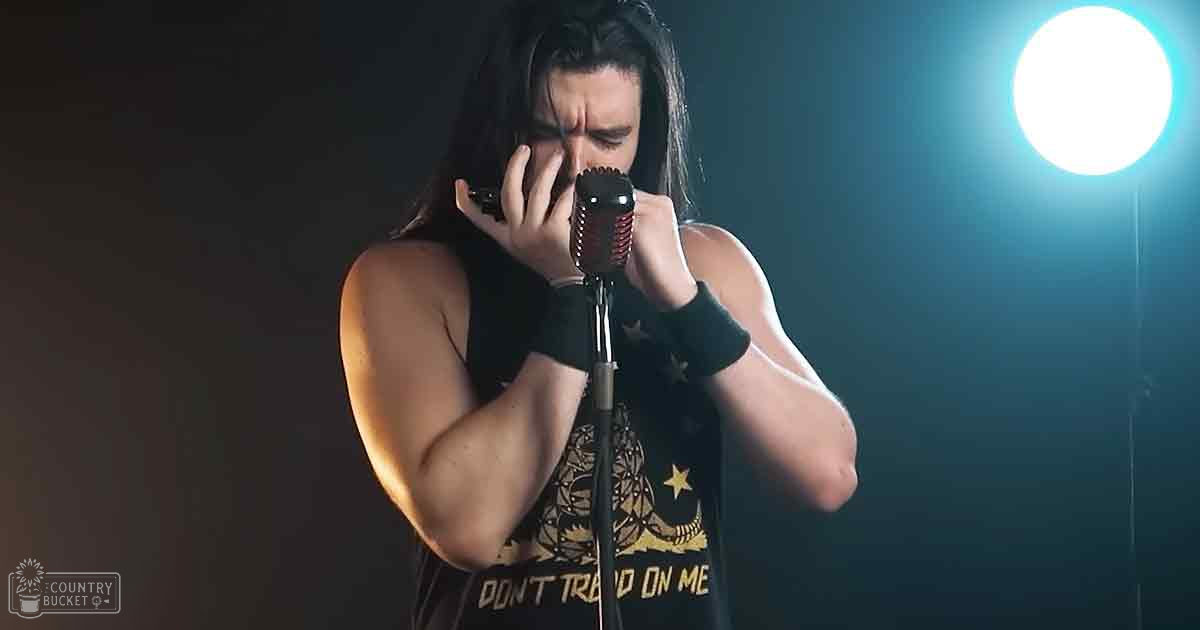 A young adult male singer in a fitted sleeveless tank top with graphic design, fingerless gloves, performing on stage under dramatic lighting.