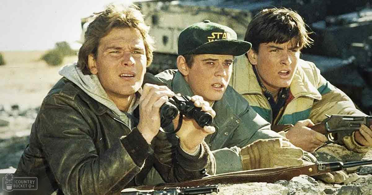 A group of young adult males in a rugged outdoor setting, possibly for military or survival training; they wear durable jackets suitable for such environments.