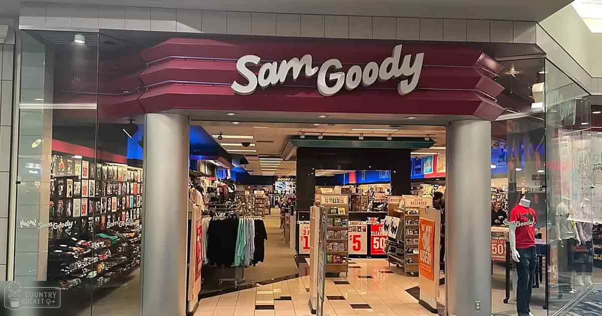 Sam Goody store interior with shelves, discounts signs, racks of clothes, tiled floor in shopping mall.