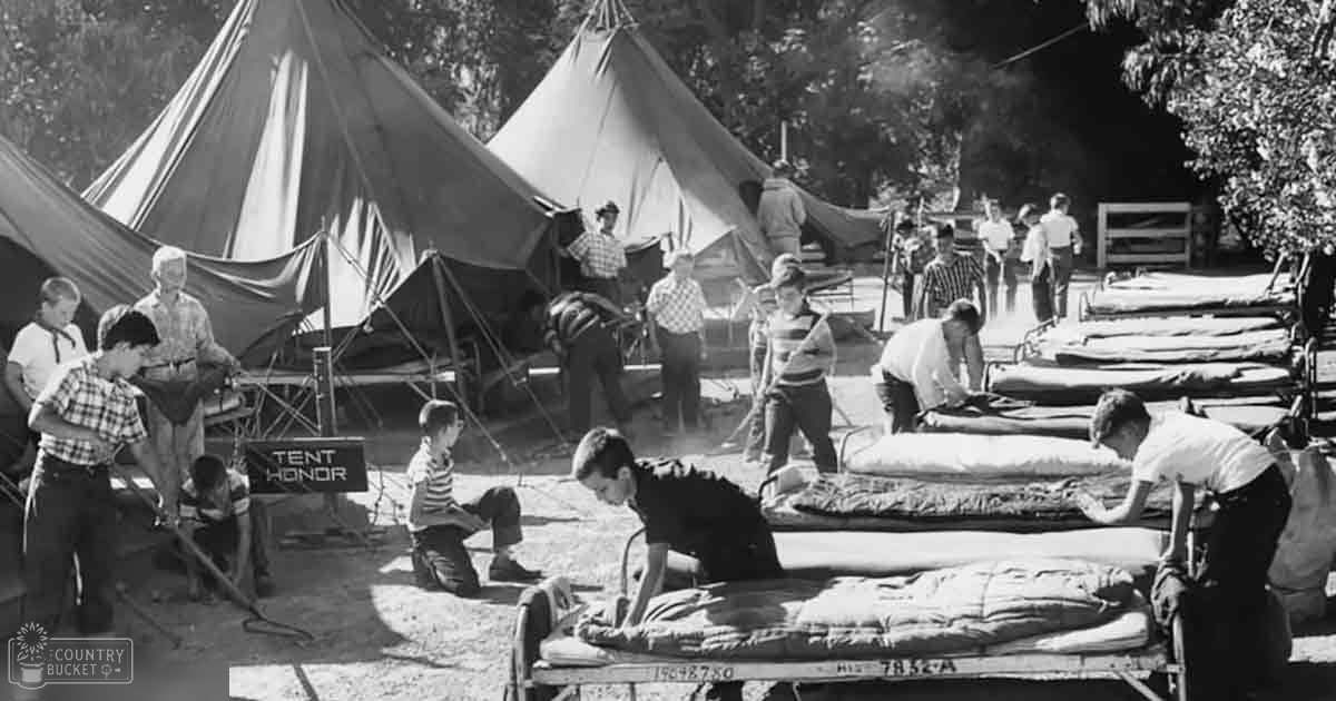 Children playing outdoors at a campsite with tents and sleeping bags under natural daylight during spring or summer.