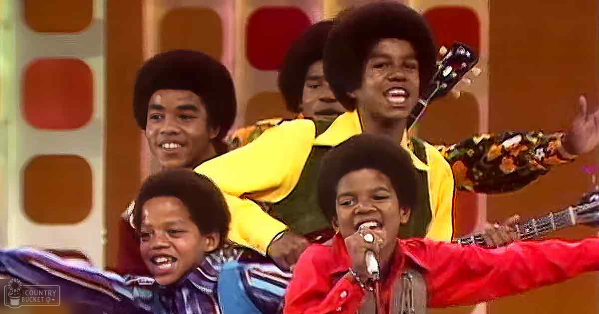 Children performing on stage with colorful outfits against a vibrant backdrop of orange, red, and yellow geometric patterns.