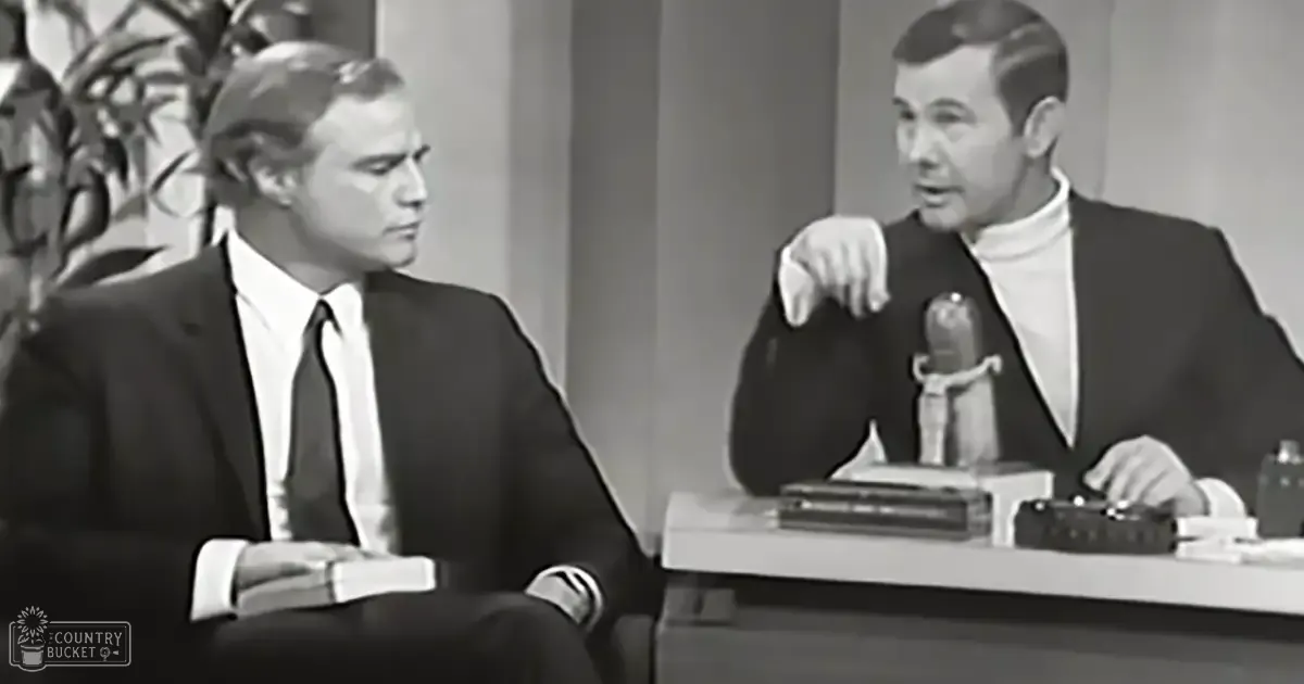 Two middle-aged to older adult males in formal attire, seated at a desk with books and papers, against an indoor studio backdrop typical of mid-20th century broadcasting.
