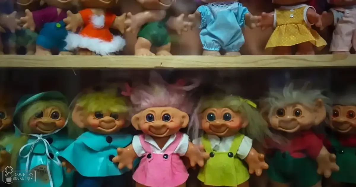 Troll dolls in a display case with wooden shelf, indoors.