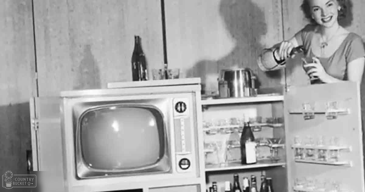 A vintage television set prominently displayed in a kitchen setting with shelves of bottles and glassware behind it.
