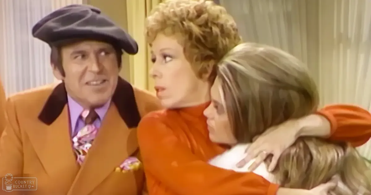 Indoor domestic setting with curtains, soft lighting; three adults in bright orange 1970s attire