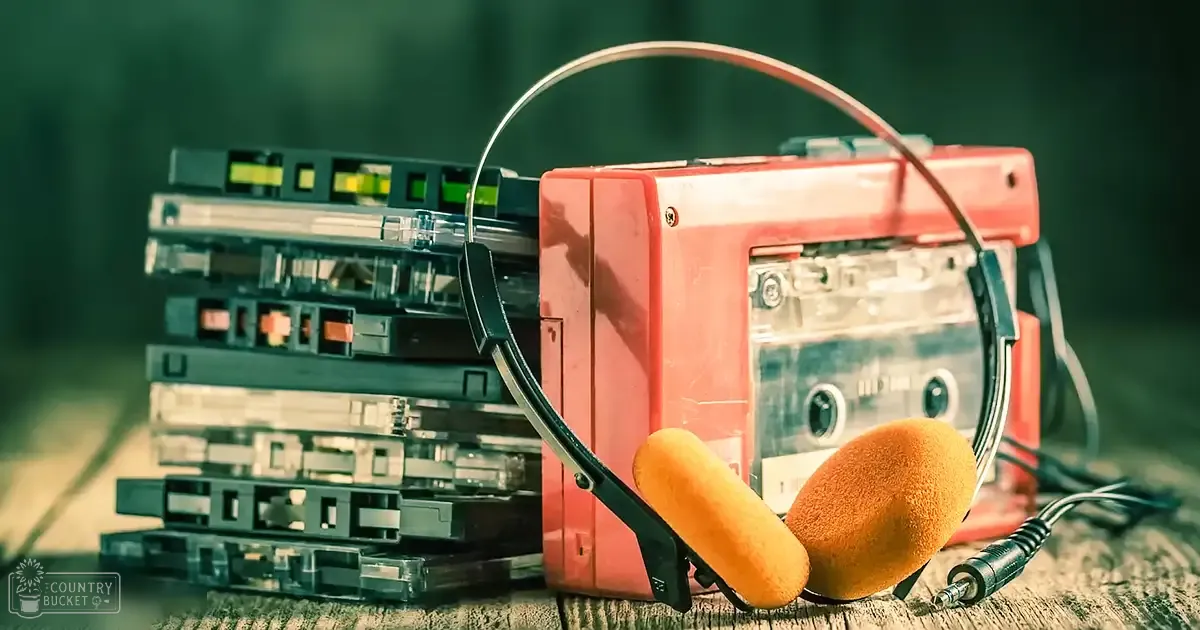 A retro cassette player with headphones, red portable device, black tapes, orange-brown foam ear cushions, indoor setting, evening lighting.