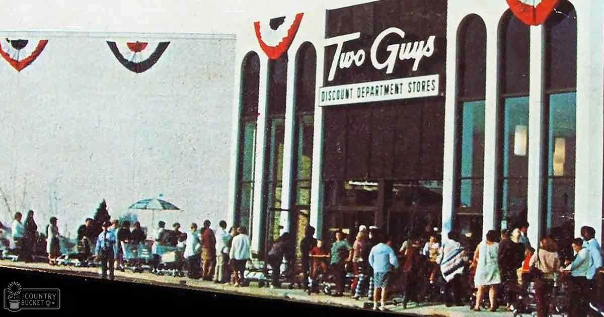 A storefront called 'Two Guys Discount Department Stores' with a variety of people in casual attire walking by on an urban street scene; spring or summer, daytime light.