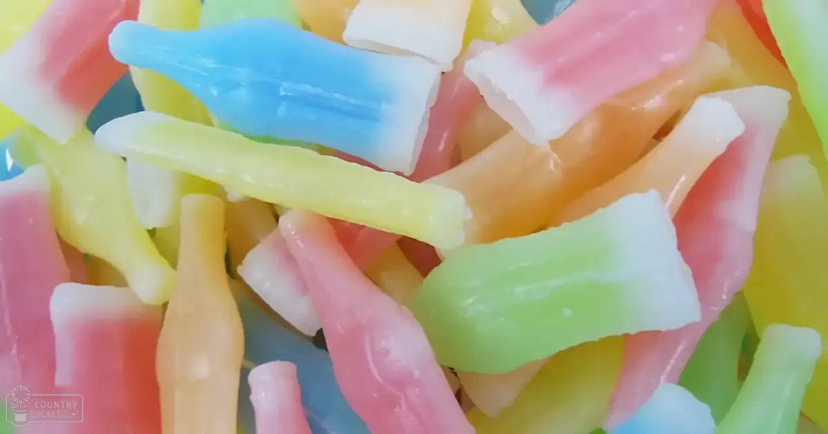 Close-up view of colorful gummy candies including shapes like worms and squares; vibrant shades of pink, blue, yellow, green, and white.