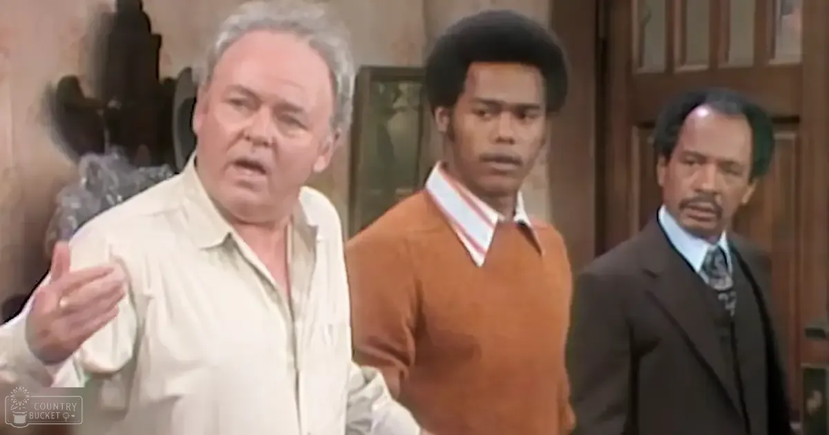 Three middle-aged men wearing casual attire indoors with wooden furniture and framed artwork.