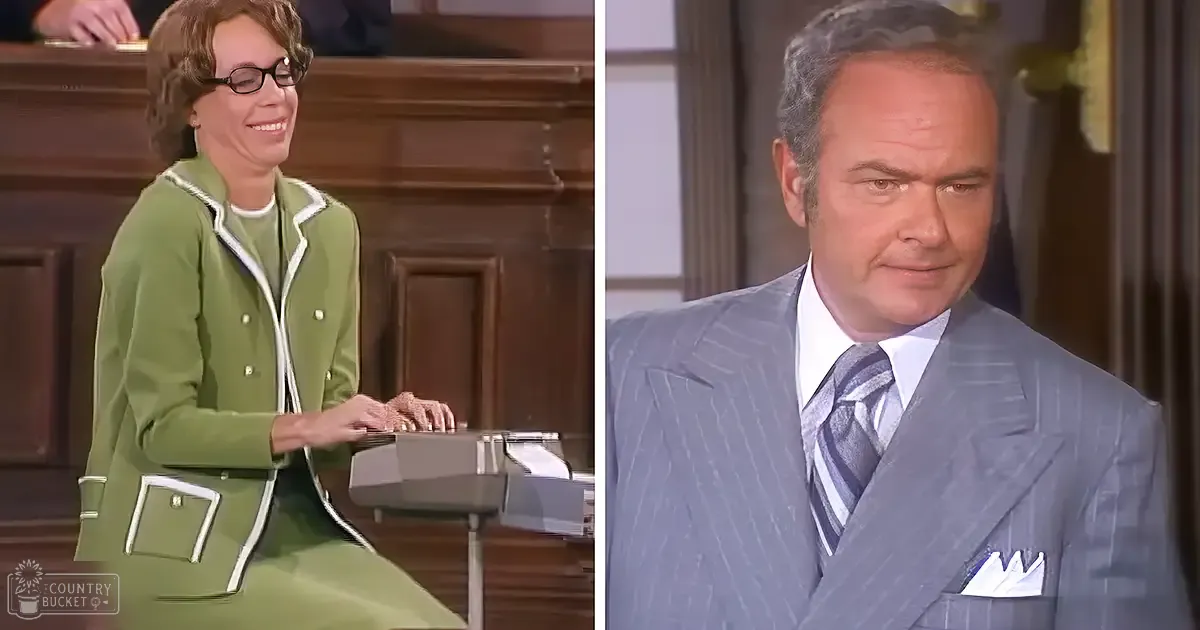 A woman and a man are depicted in an office setting. The woman wears a green suit with white trim, while the man is dressed in a light gray pinstriped suit.