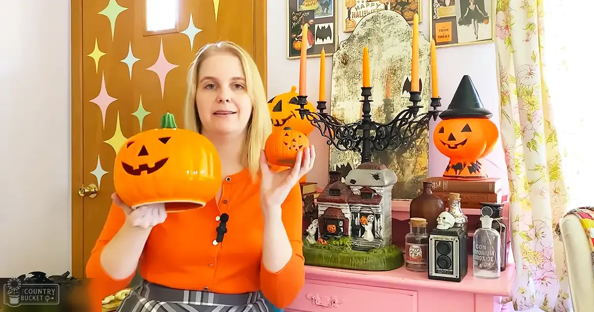 A young adult female in a relaxed fit, collared button-up shirt with long sleeves and bright orange color stands amidst a Halloween-themed setting.
