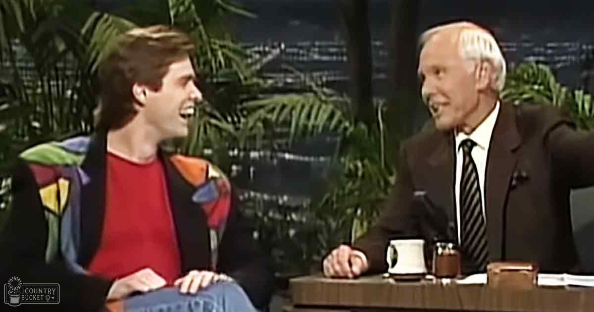 Two individuals engaged in conversation on a talk show set with potted greenery and studio lighting.