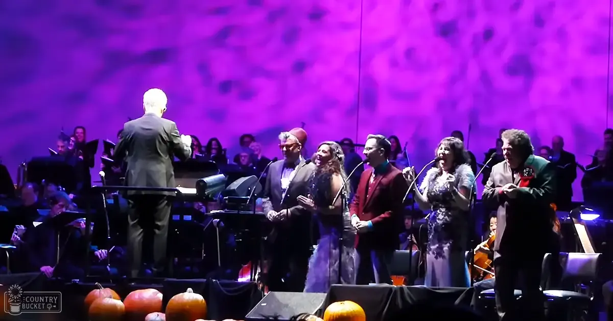 A musical performance with a conductor and singers in a concert hall during autumn.