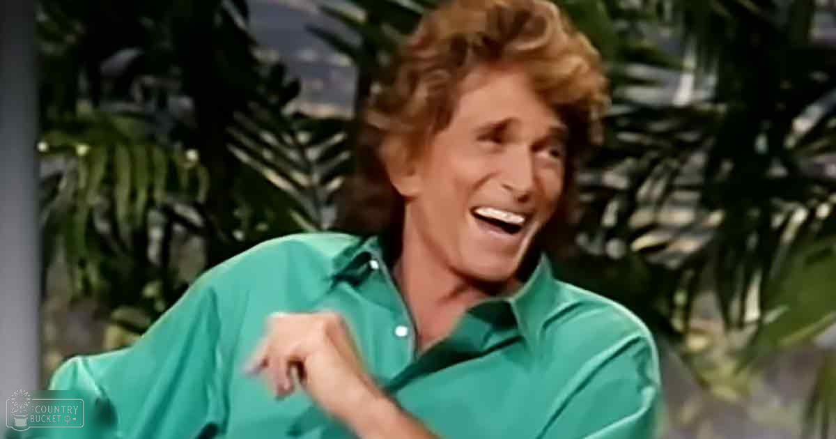 An older adult male wearing a teal green long-sleeved button-up shirt with relaxed fit, collar, and solid color stands outdoors amidst tropical foliage under natural daylight.