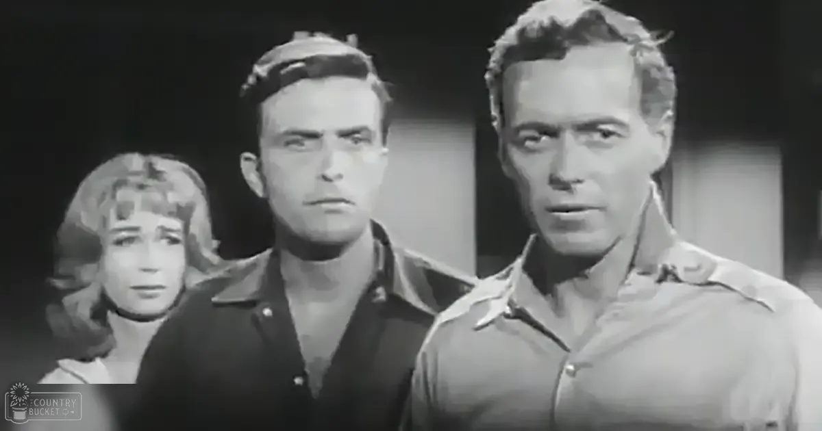 Indoor scene with three adults in mid-20th-century attire; two men in collared shirts and a woman in a high-necked dress, possibly evening or night setting.