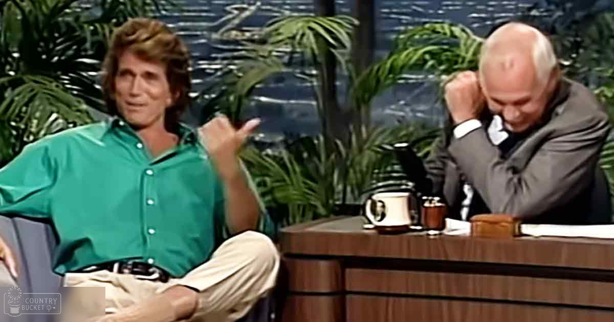 Two middle-aged men in a talk show set with an indoor studio background and lush greenery, suggesting a tropical theme.