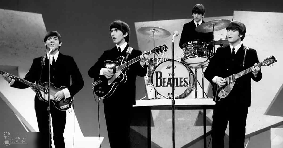 The Beatles performing or recording in a simple studio setup with geometric shapes and a plain backdrop, suggesting an indoor recording environment from the 1960s era.