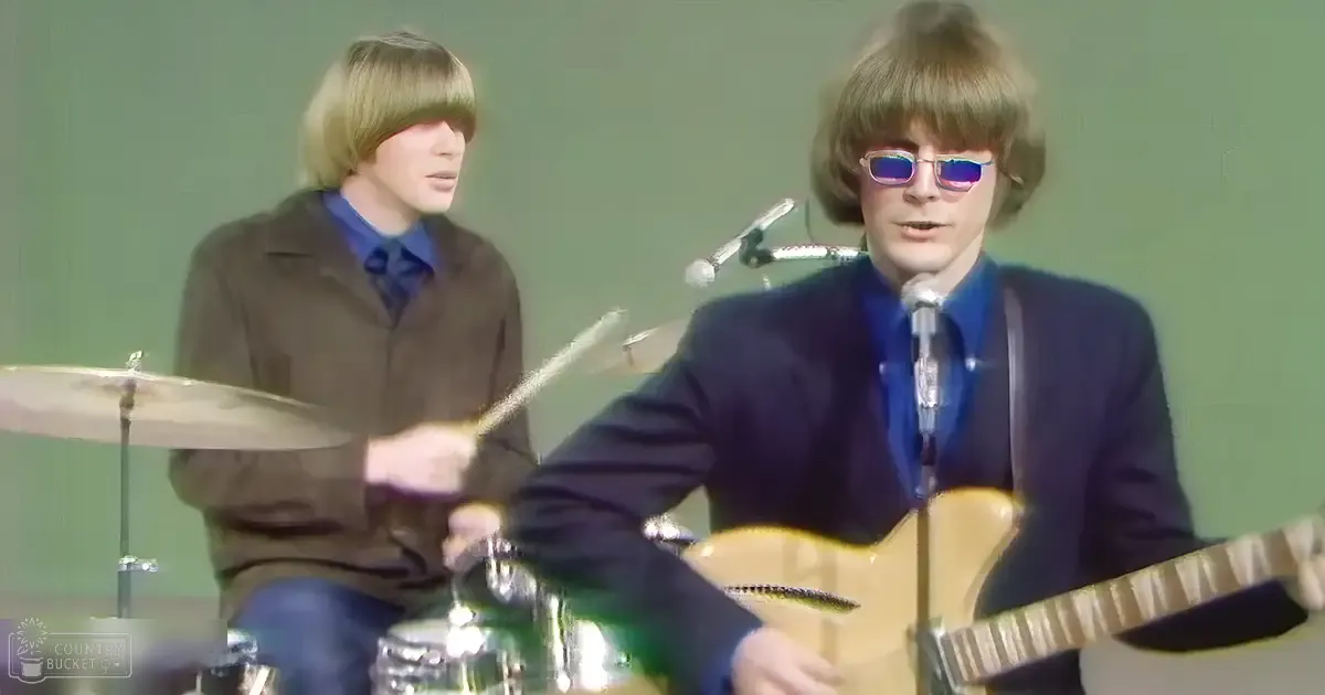 A musical performance by young adults in a light green studio setting with microphones and a drum set, focusing on the performers' attire and instruments.