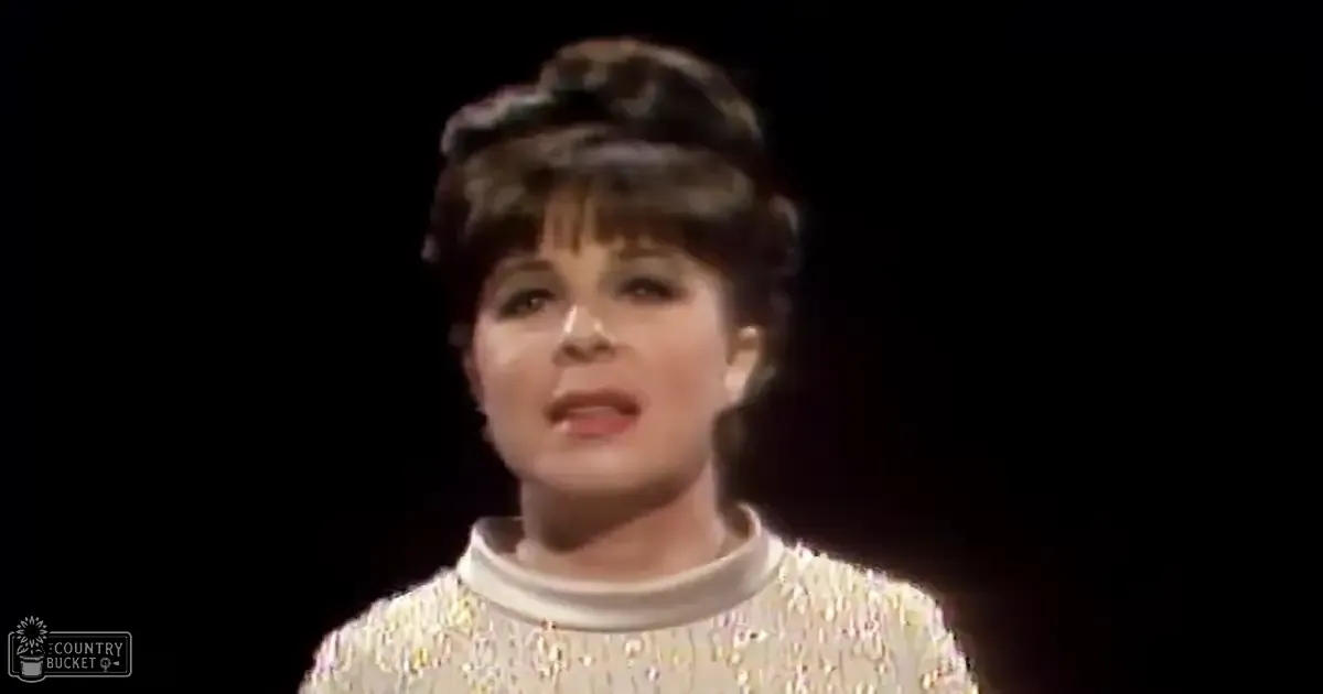 A middle-aged female wearing a textured, sequined white dress from the late 20th century in a studio setting with focused lighting on her.