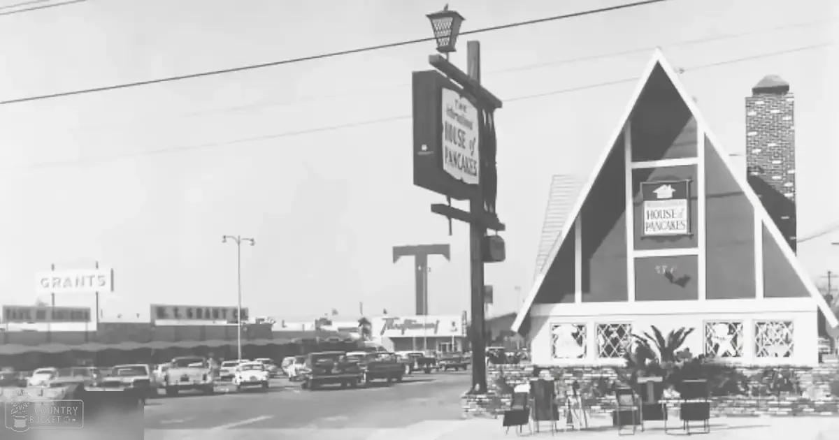 A triangular-shaped building labeled 'The International House of Pancakes' in an urban area with commercial establishments and outdoor seating.