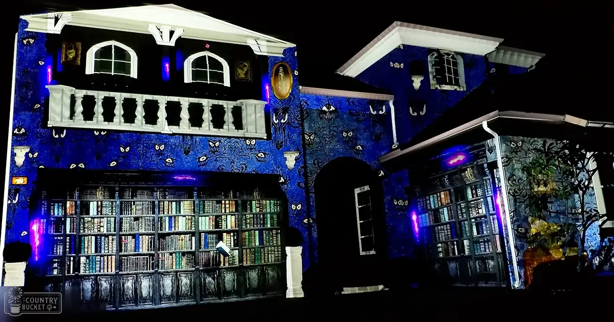 An urban library facade at night, with bookshelves, paintings, a balcony with railings, and an arched doorway.