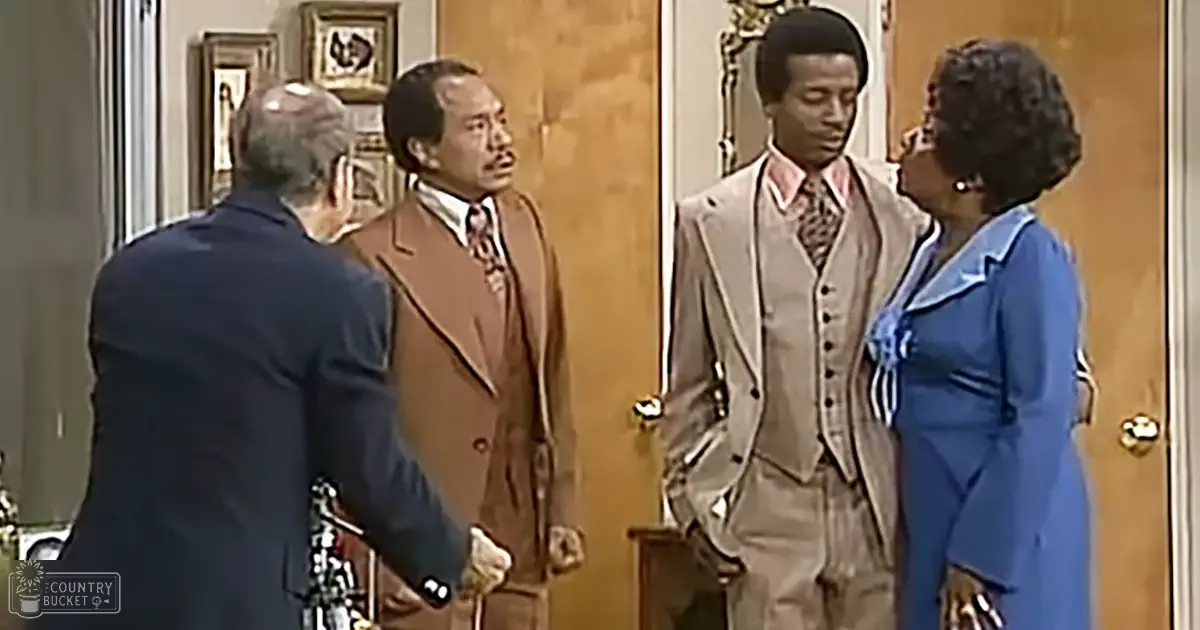Four adults in formal attire indoors, with wooden door and framed art visible.