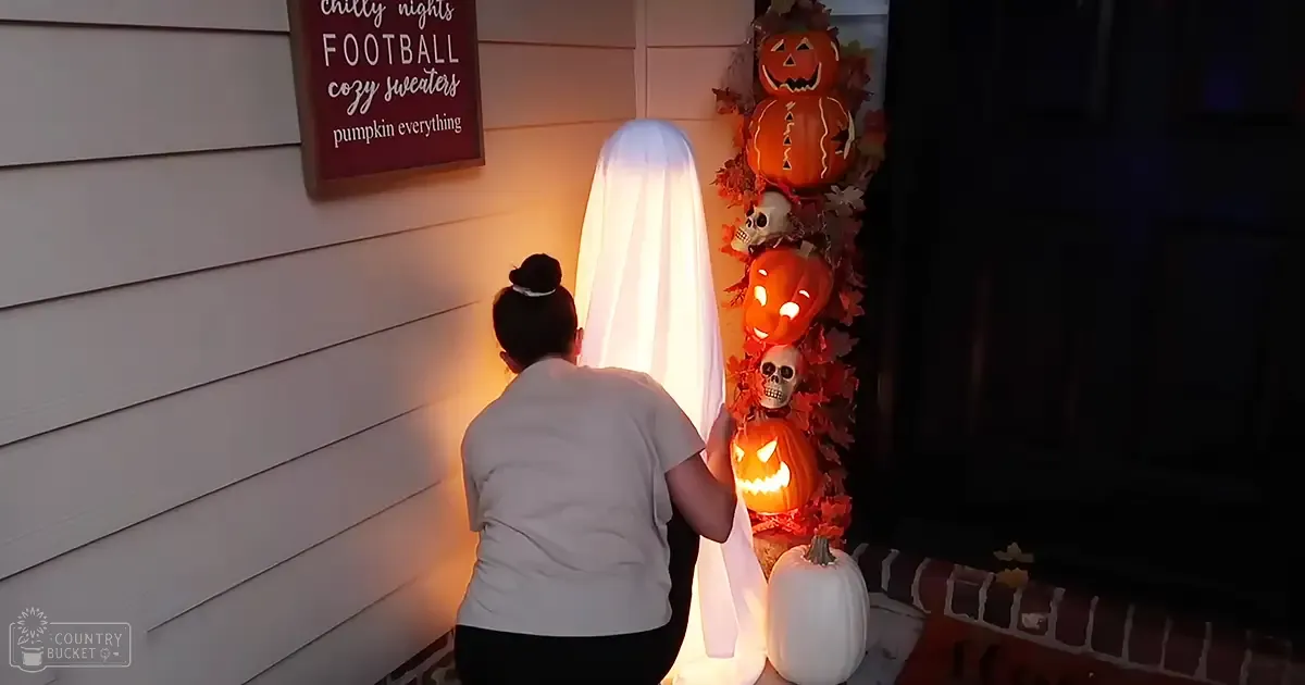 A young adult female decorating for Halloween at home with a focus on seasonal decorations and glowing pumpkins.