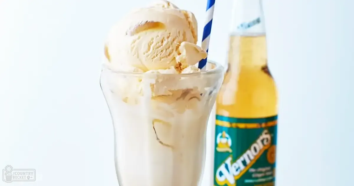 A creamy white milkshake topped with vanilla ice cream, served in a tall glass with a blue and white striped straw; labeled 'Vernors' soda bottle nearby;