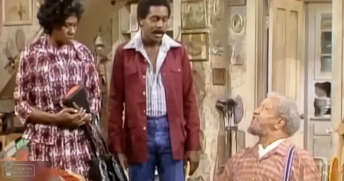 An indoor home environment with three adults in a sitcom setting: one adult female wearing a patterned dress and holding a small black purse, an adult male in a red corduroy jacket over a striped shirt and blue jeans, and another older adult male in a plaid shirt with glasses. The scene includes a wooden cabinet with glass doors and wall decorations.