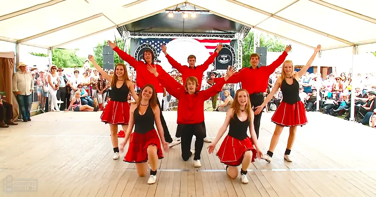 Children and teens performing a dance routine at an outdoor summer festival in Texas under clear daylight conditions.