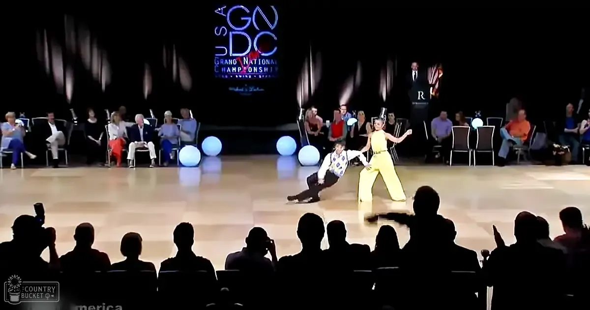 A dance performance at the USA Grand National Championship takes place in an indoor arena, with dancers wearing casual attire and spectators seated around the floor.