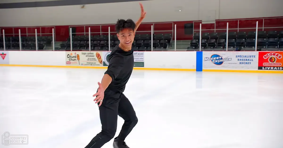 A young adult male figure skating on an indoor ice rink with red barrier walls and banners reading 'Hockey Experts,' 'Specialiste Baseball Hockey,' and 'Scores Livrais.' The setting suggests a community sports complex.