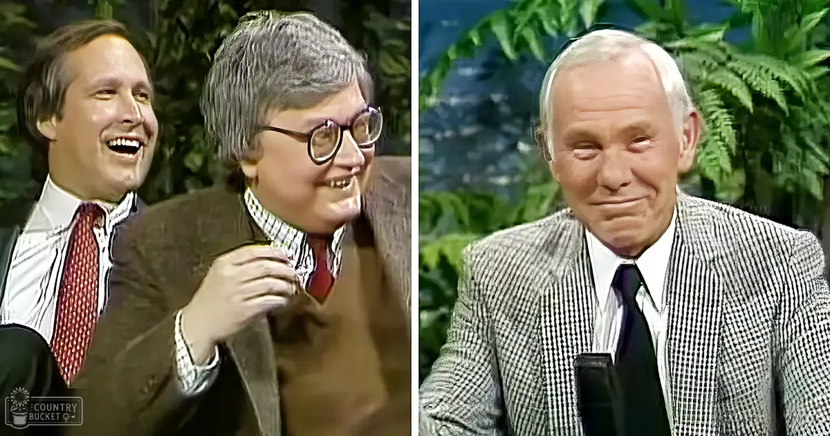 Talk show set with two adult males in foreground; green foliage and bright indoor lighting suggest a professional studio environment.