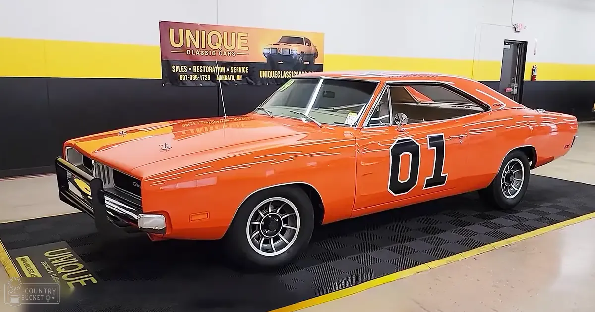 A classic orange muscle car with '01' painted on its side displayed indoors at Unique Classic Cars.