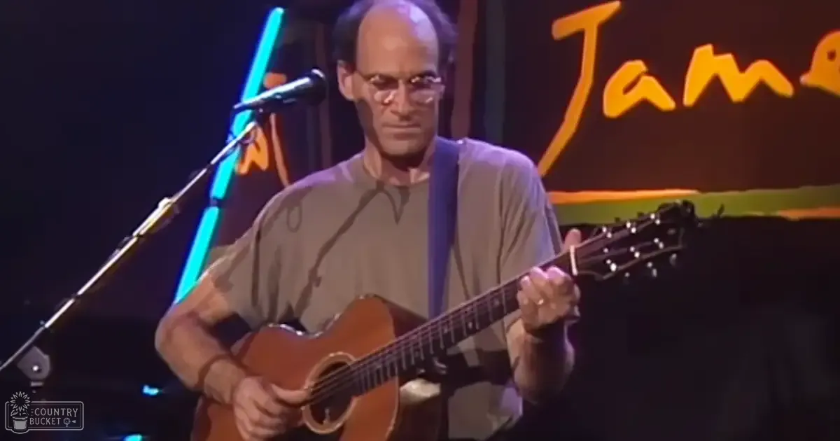 Middle-aged man playing guitar in a performance setting with stage lighting and neon lights.