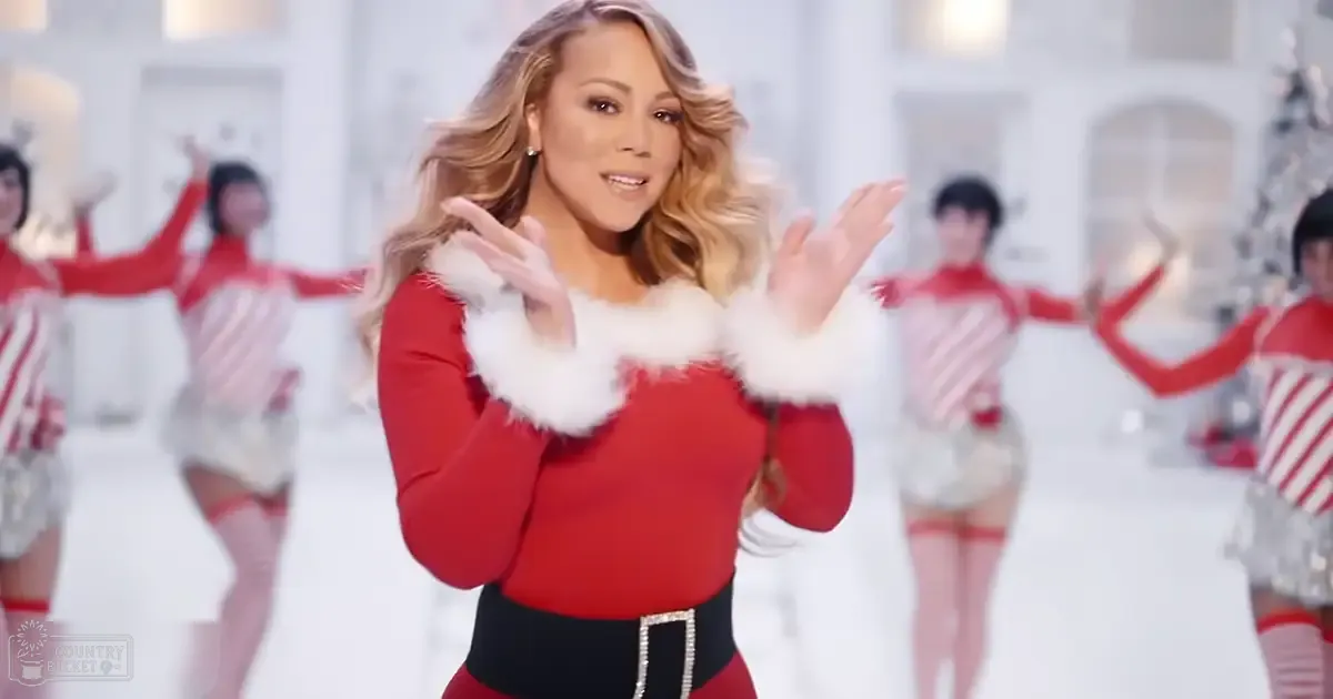 Adult female in a festive Christmas-themed setting wearing a red outfit with white fur trim and black belt, surrounded by children in similar costumes.