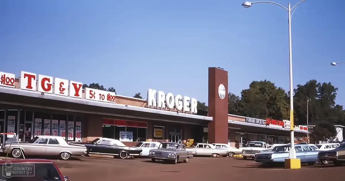 Vintage cars parked outside a Kroger grocery store in an outdoor parking lot with clear skies during daytime.