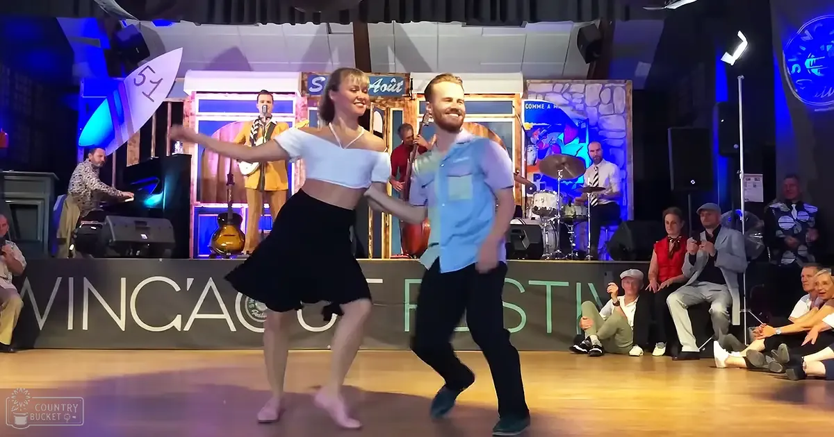 A couple dancing at an outdoor festival, wearing retro-inspired outfits and surrounded by band members playing musical instruments.