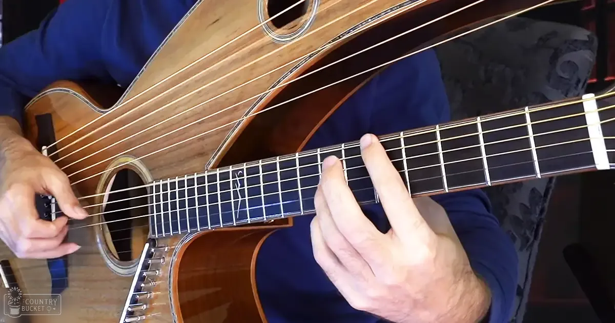 Adult male playing an acoustic guitar in a modern casual setting with natural light, indoors during the daytime.