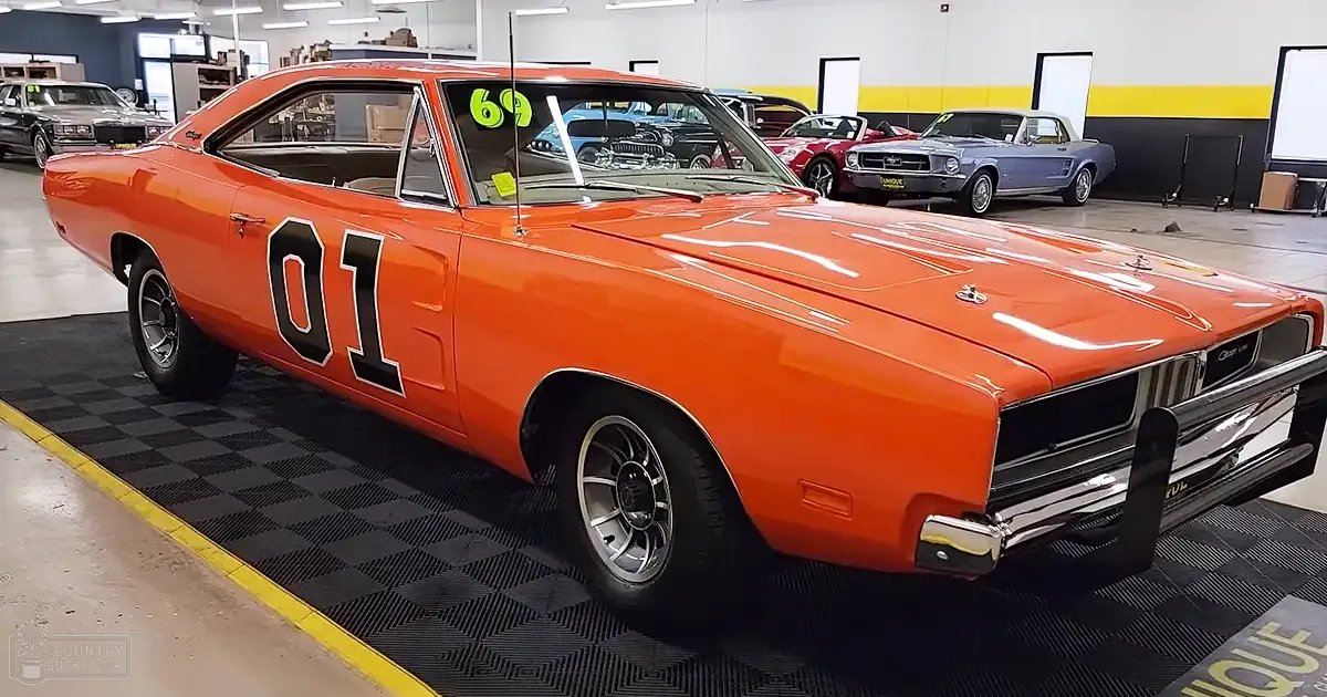 1969 Dodge Charger 'General Lee' replica car with bright orange paint in an indoor showroom setting.