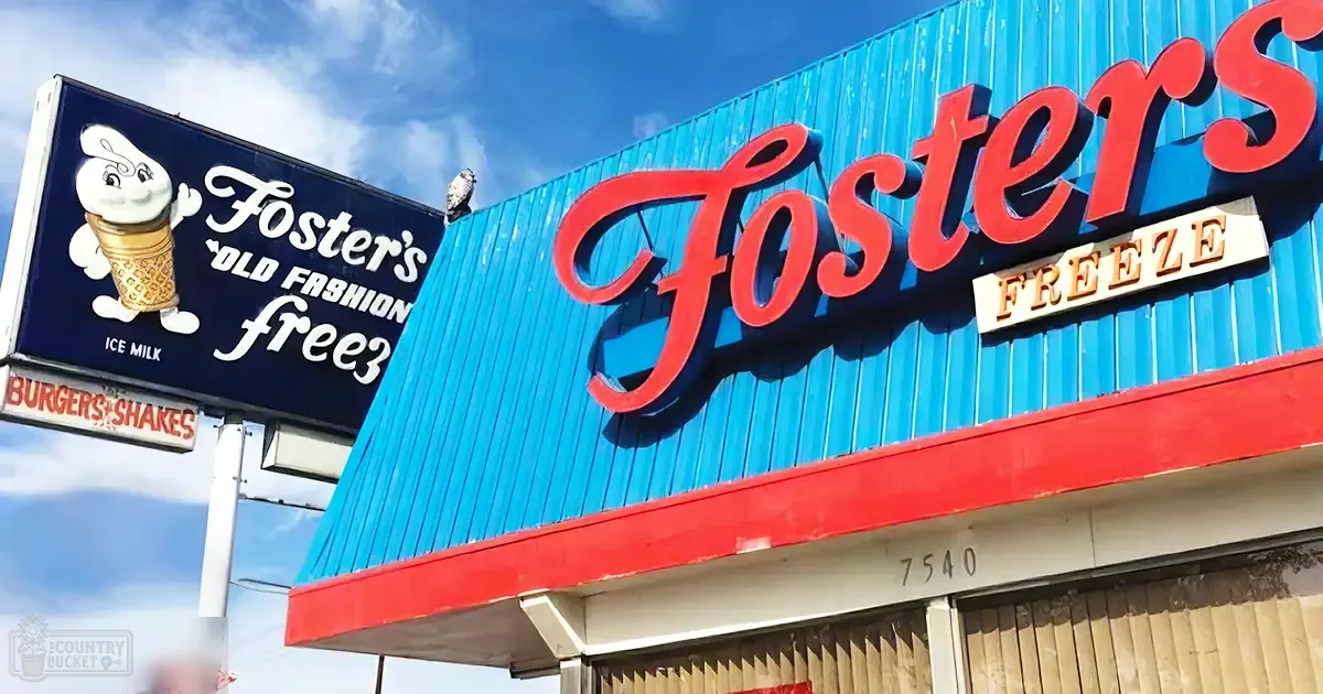 Foster's Freeze ice cream shop in an urban area, clear skies, bright sunlight, blue siding with red trim, white cartoon character holding an ice cream cone.