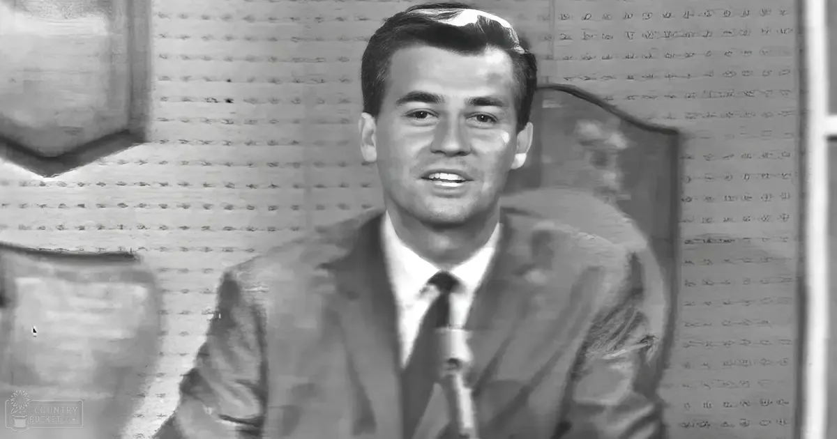 Adult male wearing a tailored mid-20th-century suit and tie in an indoor optician's shop with rows of small holes on the wall.