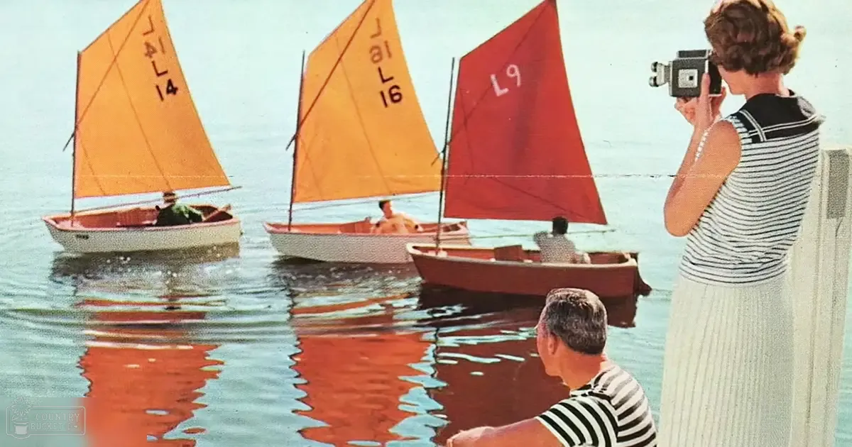 A woman films sailboats with a vintage camera at a waterfront marina, surrounded by young adults in casual summer attire on calm waters under clear skies.
