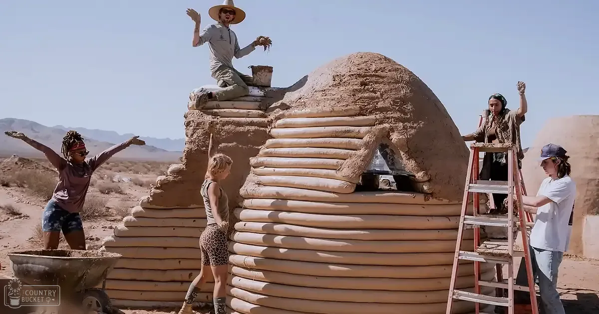 A group of people working together to build an adobe structure in a desert environment under clear blue skies.