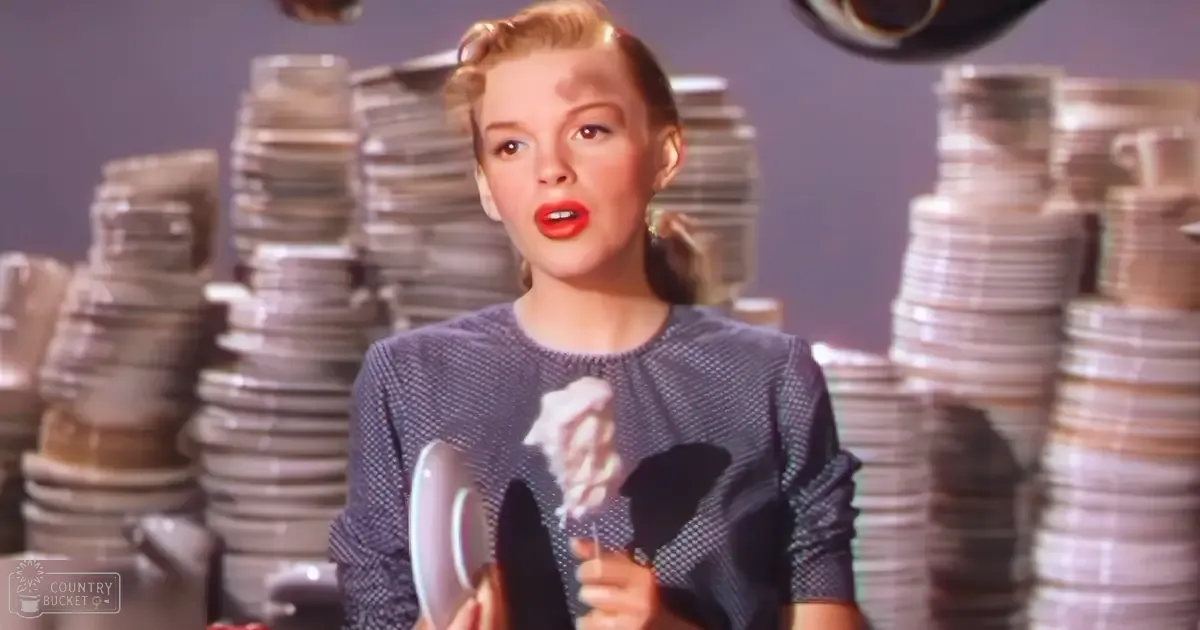 A young adult female in a dark blue dress with ruffled neckline, holding a plate and napkin indoors.