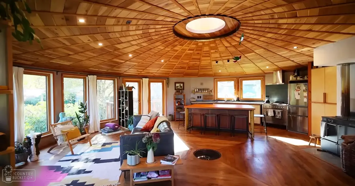 A modern home interior with large windows showing spring or summer foliage outside.