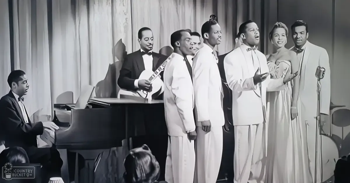 Adult male musicians in formal attire perform on stage with a grand piano under artificial evening lighting.